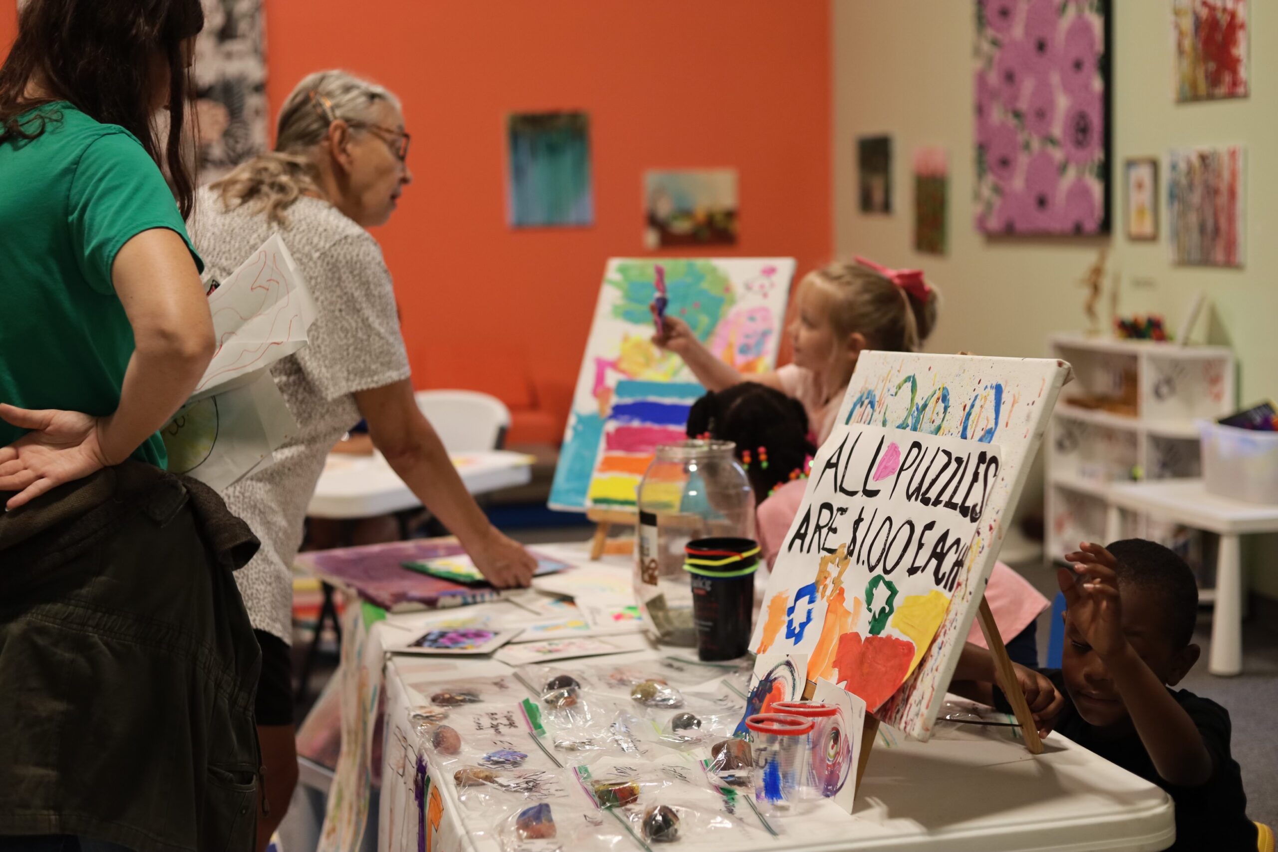 Adults look at art products created by campers at Artrepreneur Camp