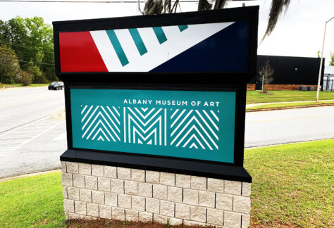 Albany Museum of Art logo in white on a teal background in one face of a three-sided roadside sign